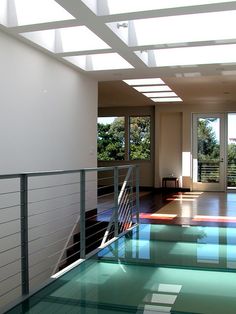 an indoor swimming pool with stairs leading up to the second floor and glass railings