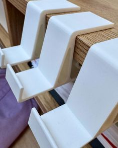 three white plastic chairs sitting on top of a wooden table next to a purple bag