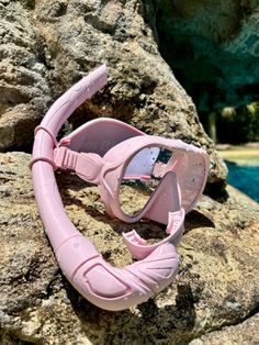 a pair of pink goggles sitting on top of a rock