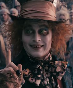 a man dressed up as the mad hatter with his hands in the air and pointing