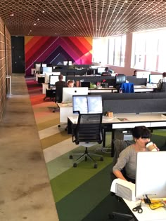 two people sitting at desks in an office with colorful walls and carpeted floors