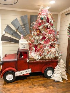 an old red truck with a christmas tree in the back is decorated and ready to be put on display