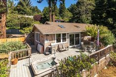 a house with a hot tub on the deck and trees in the backround