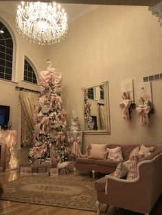 a living room with a christmas tree in the corner and pink decorations on the wall