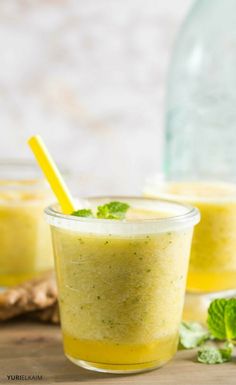 two glasses filled with green smoothie and garnished with mint on the side