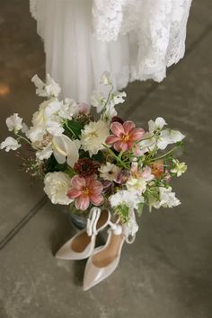 a bouquet of flowers sitting on top of a pair of shoes next to a dress