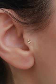 a close up of a person's ear with a small gold anchor on it