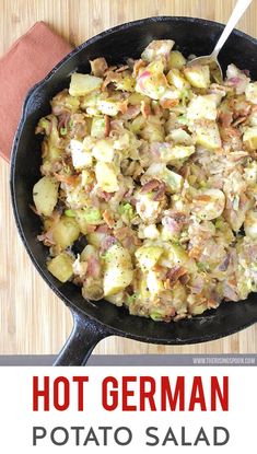 a skillet filled with potatoes and meat on top of a wooden table next to a red napkin