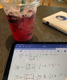 a tablet with writing on it next to a drink