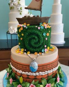 a multi layer cake decorated with flowers and a ship in the middle, on top of a table