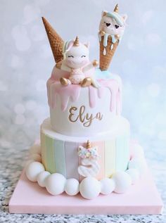 a birthday cake with an ice cream cone and unicorns on top is decorated in pastel colors