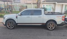 a white pick up truck parked in front of a house next to a playground area