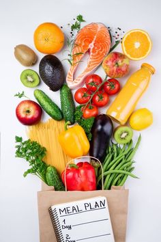 a grocery bag full of fresh fruits and vegetables next to a meal plan on a white background