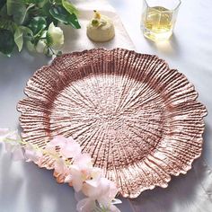 a pink plate sitting on top of a table next to flowers