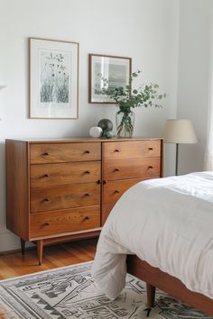 a bedroom with a bed, dresser and pictures on the wall