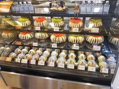 an assortment of desserts on display in a glass case at a deli counter