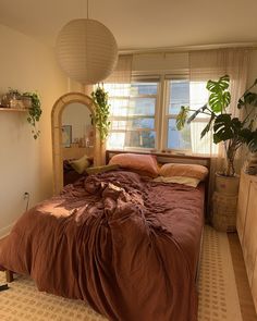 a bed sitting in a bedroom next to a window with potted plants on it