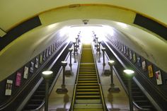 an escalator in a subway station with people walking up and down the stairs