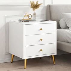 a white night stand with two drawers and a clock on it next to a couch