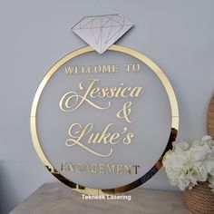 the welcome sign for an engaged couple is displayed on a table with flowers and vases