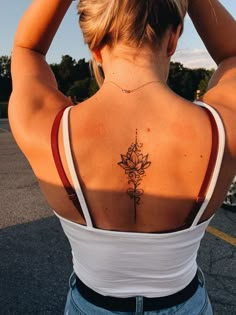 a woman with a flower tattoo on her back is standing in the parking lot and looking down