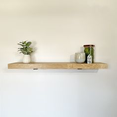 two vases are sitting on top of a wooden shelf next to a potted plant