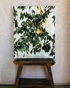 an easel with a painting on it sitting in front of a wall