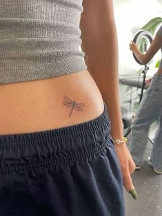 a woman with a small dragonfly tattoo on her stomach