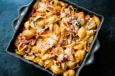 a casserole dish filled with pasta and cheese on a blue tablecloth next to a fork