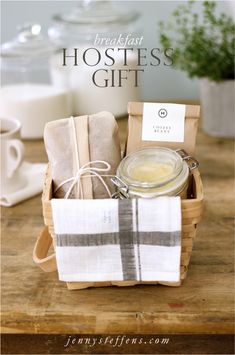 a wooden table topped with a basket filled with tea bags and coffee cups next to a jar