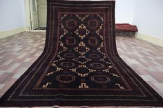 a large black and gold rug on the ground in a room with tile flooring