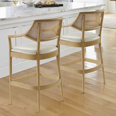 two wooden chairs sitting on top of a hard wood floor next to a kitchen counter