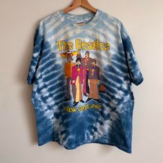 a tie - dye shirt with the beatles on it hanging up against a white wall