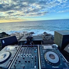 dj equipment sitting on top of a wooden table next to the ocean