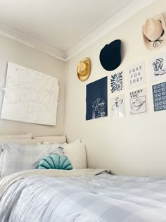 a bedroom with hats on the wall and pictures above the bed, along with other items