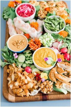 a platter filled with lots of different types of food and dipping sauces on top of it