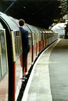 a man standing on the side of a train at a station