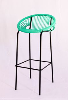 a green chair sitting on top of a black metal frame bar stool with arms and legs