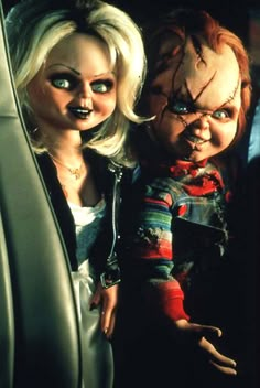 two dolls in the back seat of a car, one is holding a baby doll