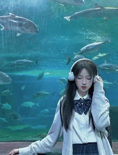 a girl with headphones standing in front of an aquarium