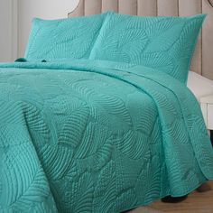 a bed with a turquoise comforter and matching pillows