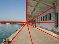 the red lines are drawn on the side of an old building by the water's edge