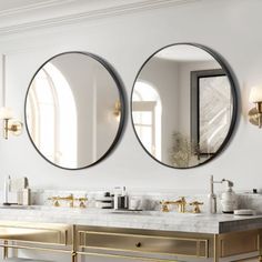 two round mirrors hanging on the side of a wall above a double sink in a bathroom