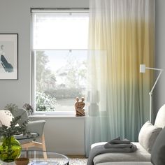 a living room filled with furniture and a large window covered in yellow drapes next to a white couch