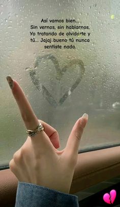 a person holding their hand up in front of a window with a heart drawn on it