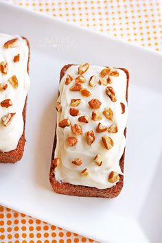 two pieces of bread with white frosting and nuts on them sitting on a plate