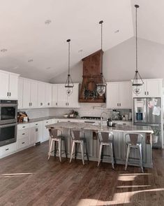 a large kitchen with white cabinets and wooden floors