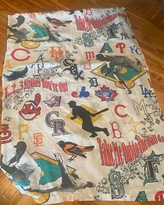 an image of a baseball themed blanket on the floor with wood floors in the background