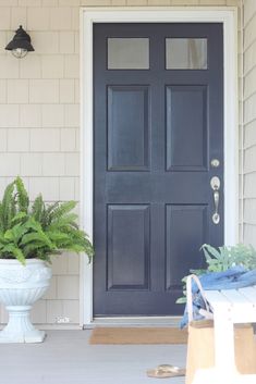 a blue front door with potted plants on the side and a white planter next to it