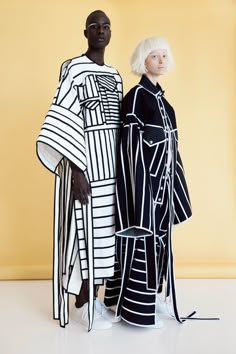 two people standing next to each other wearing black and white outfits with stripes on them